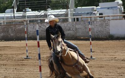 young cowgirl running a horse through the pole bending pattern