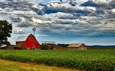 a red barn next to a field of green