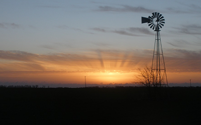 a windmill in front of a sunset
