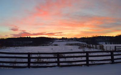 Sun rising over a ranch during winter.