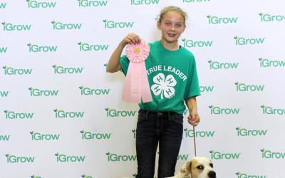 female 4-H youth with her white dog and their pink rosette