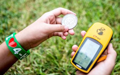 hands holding a 4-H coin and a gps navigational device