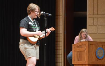 female 4-H youth performing on stage with a ukulele