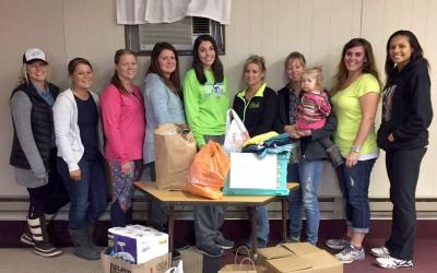 group of young women standing by a table of donated items