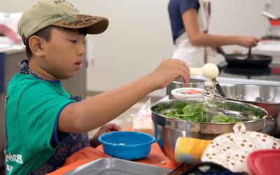 male 4-H youth preparing a salad in a silver mixing bowl