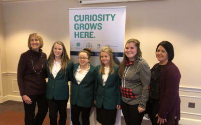 an image with 6 women posing in front of a banner.