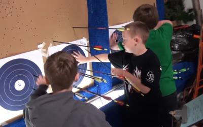 three male 4-H youth retrieving arrows from archery targets