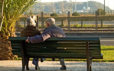 retired couple sitting on a park bench overlooking a bluff.
