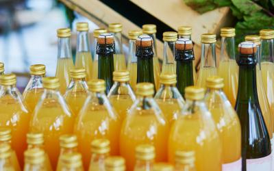 Rows of bottled juice on display at a farmers market.