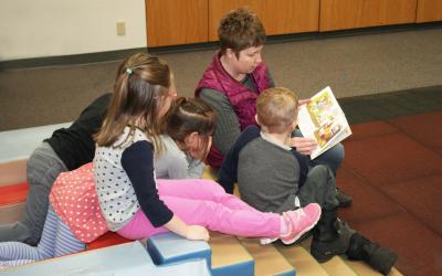 SDSU Extension Early Childhood Field Specialist Audrey Rider reading a book to a group of four children.