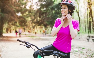 Bike safety Woman in pink shirt buckling helmet under her chin