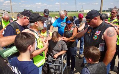 Jackie Rhode and members of the Christian Motorcyclist Association huddling for a group prayer.