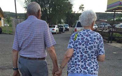 Two older people holding hands while walking.