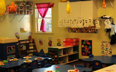 Lunch room in a daycare facility with plates set on the tables and fall decorations in the background.
