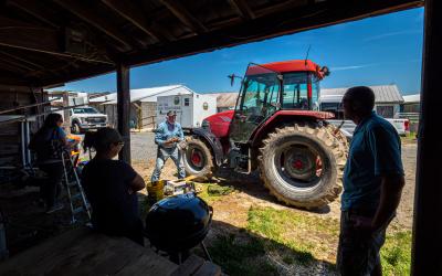 A group of dairy employees having a discussion around a barbecue grill.