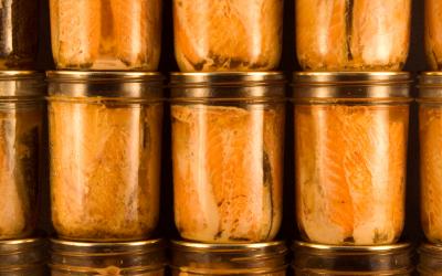 Several jars of canned salmon filets stacked neatly on top of each other.
