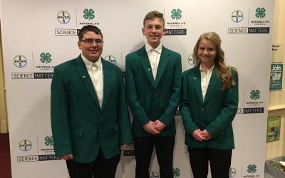 an image of three youth in green jackets in front of a display