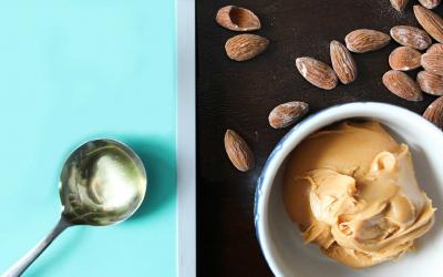 Almonds, a tablespoon of oil, and almond butter sitting on a countertop