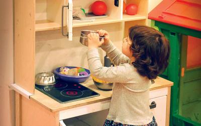 Young girl pretending to cook in a children's play kitchen.