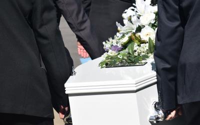 A group of men carrying a white coffin.