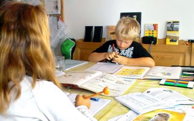 A young male student studying at the kitchen table with an older sister.