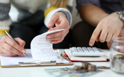 A young couple reviewing their family budget on a clipboard.