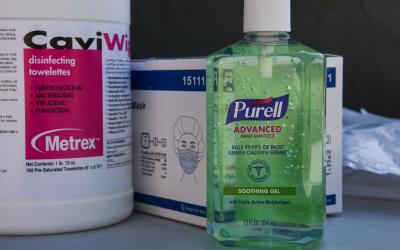 Hand sanitizer, disinfecting wipes, and respirators sitting on a table.
