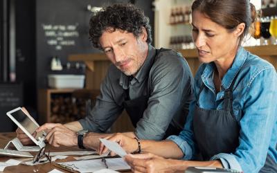 a man and a woman sitting at a desk looking at paperwork