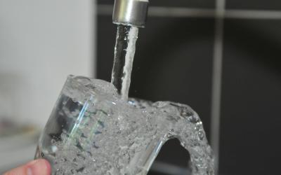 A glass of water being filled from a kitchen sink tap.