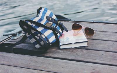 a book, sunglasses, and bag sitting on a dock by the water.