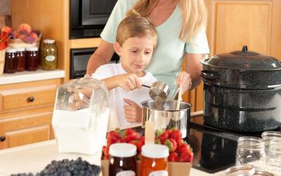 Mother with child cooking homemade jam in a kitchen.