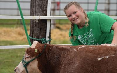 Ellie Wagner posing next to a cow at the Yankton County Fair.