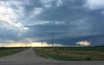Country road with a thunderstorm approaching in the distance.
