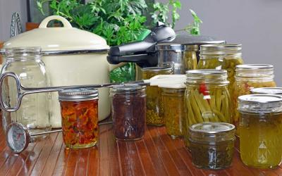 Home canning supplies and canned vegetables arranged on a countertop.