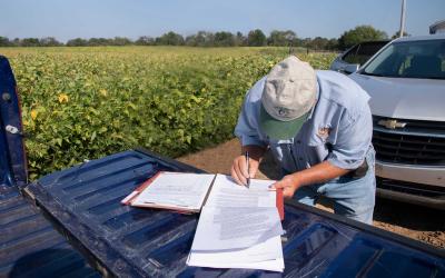 Farmer signing a lease on the tailgate of a pickup.