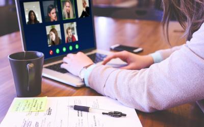 a woman using a laptop to join a video meeting with other people