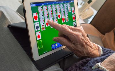 an older adult playing solitaire on an iPad