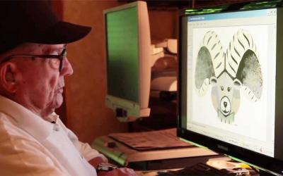 An older male adult composing an illustration on a computer screen.