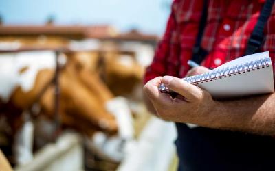 Rancher holding a notepad beside a feed bunk.