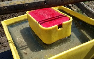 A large, yellow automatic cattle waterer installed in a feedlot.