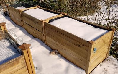 Snow-covered raised beds ina community garden.