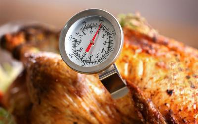A golden, roast turkey with a food thermometer in it.