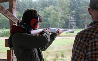 a young man practicing shooting with a shotgun