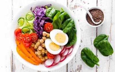A salad bowl filled with a variety of fresh vegetables and slived eggs.