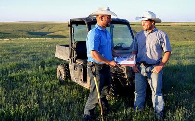 Two ranchers in a pasture reviewing a mangement plan.