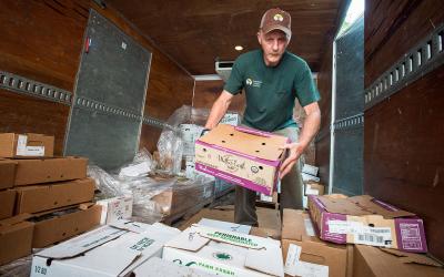 Producer unloading fresh, farm-grown produce from a delivery truck at a super market.