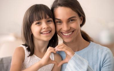 Daughter and happy mother join hands in heart shape.