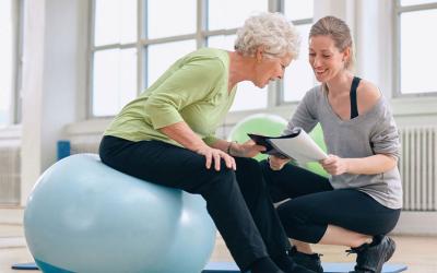 Senior woman and health coach looking at a health report in a gym.