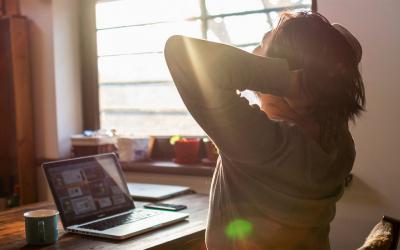 Young man stretching at a remote work station in his home.