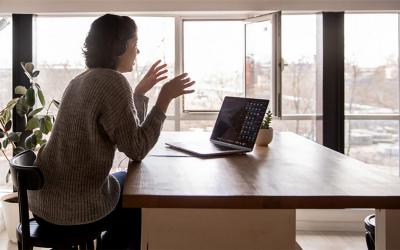 Young woman participating in a video conference at a remote work station.